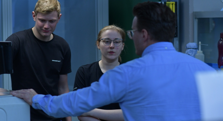 Ung mand og ung kvinde, som er under oplæring af ældre kollega hos virksomheden Grundfos